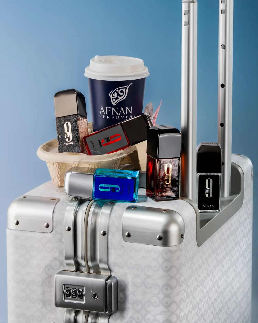 Small bottles on a silver suitcase beside a takeaway coffee